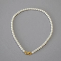 Detail of round faux pearl necklace with golden infinity clasp on grey background - Creamy White Necklace 6mm
