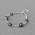 Vista macro di perle barocche scure e perline d'argento su una collana corta - Bracciale