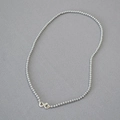 Close-up of minimalist silver beaded necklace with metal lobster clasp on grey fabric - Silver Gray Necklace 3mm
