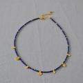 Dettaglio della collana con perline di lapislazzuli e pendenti a moneta dorata martellata - Lapislazzuli