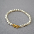 Close-up of elegant round cream pearls with a polished gold lobster clasp detail - Creamy White Bracelet 5mm