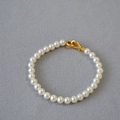 Macro shot of elegant round white pearls with a golden streamlined lobster clasp closure - 6mm