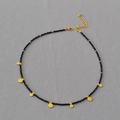 Dettaglio della collana bohémien con perline nere sfaccettate e ciondoli a moneta d'oro - Spinello nero