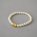 Baroque style elastic bracelet with cream white pearls and a gold irregular metal bead - 6mm