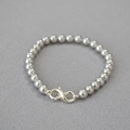 Detail of gray pearl bracelet featuring a silver infinity clasp on textured fabric - Silver Gray Bracelet 6mm
