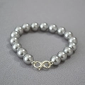 Close-up of grey high-luster pearls with silver spiral clasp on textured background - Silver Gray Bracelet 10mm