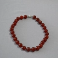 Detail van rode agaat kralenketting met glanzende ronde stenen en zilveren sluiting - 14mm Rode Agaat