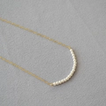 Macro detail of seventeen round pearls on a delicate gold chain for elegant daily wear - Off-white