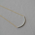 Detail of minimalist gold chain necklace featuring 16 gray pearls in curved arrangement - Silver Grey