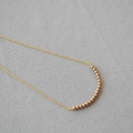 Detail of matte gold beads forming a smile curve on a minimalist necklace chain - Champagne Coffee