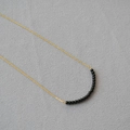 Detail of minimalist gold chain necklace with delicate black agate beads on knit fabric - Black Agate