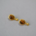 Vista macro di orecchini vintage dorati con pietre occhio di tigre e piccoli ciondoli - Occhio di tigre