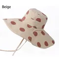 Detail view of the beige sun hat featuring large brown polka dots and a windproof chin strap - One Size 58cm / Beige