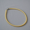 Détail d'un collier de perles dorées à haute brillance avec un fermoir magnétique argenté - 6mm