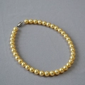 Collier de perles dorées rétro avec fermoir métallique sur fond gris texturé - 10mm