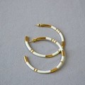 Close-up of gold-plated bamboo-joint hoop earrings with white enamel detail and silver posts - Off-white