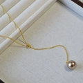 Dettaglio di un ciondolo con perla champagne su una catena d'oro sottile su vassoio di lino - Perla Artificiale Champagne