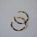 Detailed shot of large C-shaped bamboo hoop earrings with gold plating and black enamel - Black