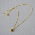 Dettaglio macro del ciondolo ovale in occhio di tigre su catena dorata sottile - Collana