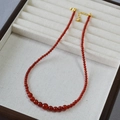 Gradient red agate beaded necklace with gold lobster clasp on a velvet tray - Red
