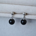 Dettaglio di orecchini minimalisti in argento con eleganti ciondoli in onice nero lucido - Agata Nera 10mm