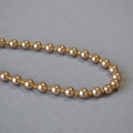 Elegante collana di perle con perle oro champagne su sfondo di tessuto grigio - 8mm / Marrone
