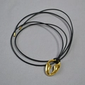 Dettaglio di un ciondolo placcato oro lucido con un elegante cordoncino nero per collana - Collana