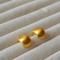 Pendientes geométricos de oro cepillado en forma de C sobre un soporte de tela rústica - Estilo de pendiente de botón dorado