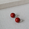 Gros plan de boucles d'oreilles rondes en émail rouge cerise sur tissu crème texturé - Rouge 10mm