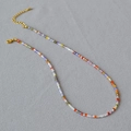 Macro detail of multi-color beaded necklace with golden lobster clasp and adjustable chain - Colorful