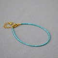 Dettaglio di un sottile bracciale di perline turchesi con chiusura a moschettone dorata - Stile Turchese Celeste Ultra-fine (Modello 1)