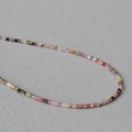 Close-up of colorful faceted natural stone beads on a minimalist necklace strand - Tourmaline