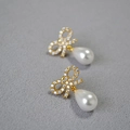 Dettaglio macro degli orecchini a fiocco dorato con zirconi e perle a goccia eleganti - Stile Fiocco Zirconia (款2)