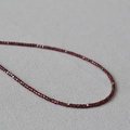 Detailaufnahme dunkelroter facettierter Steinperlen mit silbernen quadratischen Distanzstücken - Granat