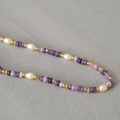 Detailed macro view of purple amethyst stones, rice pearls, and golden spacer beads - Lavender