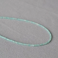 Makroaufnahme winziger 2mm facettierter hellblauer Natursteinperlen an einer Kette - Amazonit