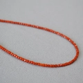 Vista macro di piccole perle a cubo in agata rosso-arancio sfaccettata su collana - Collana di perle agata Nanhong