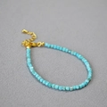 Dettaglio di bracciale con perline quadrate blu e catena regolabile dorata con ciondolo - Turchese