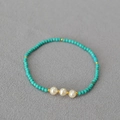 Détail macro de perles turquoise avec perles d'eau douce et séparateurs dorés sur tissu - Bracelet Verdâtre