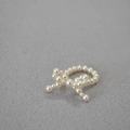 Detalle de pendientes de lazo de perlas artificiales tejidas con un brillo elegante - Anillo