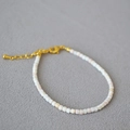 Gros plan d'un collier en perles de coquillage rose avec fermoir mousqueton doré et chaîne - Bracelet Coquille de Reine