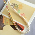 Detailed close-up of mixed necklace with colorful crystals and white pearls on gold base - Necklace