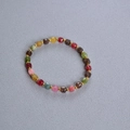 Bracelet de perles tourmaline colorées à facettes avec détails dorés sur tissu gris - Bracelet en Perles Carrées