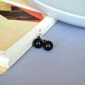 Macro detail of silver drop earrings featuring polished black onyx beads in a minimal style - 10mm