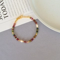 Detailed macro view of colorful gemstone beads and freshwater pearls on a delicate gold chain - Colorful