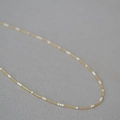Dettaglio di elegante collana in ottone placcato oro con delicate mini perle bianche - 39+5cm