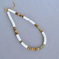 Dettaglio di collana boho con dischi di conchiglia bianchi, perle di legno e pietre verdi - Collana
