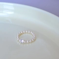 Elegant pearl beaded ring with a sparkling square-cut crystal center on a ceramic plate - Ring