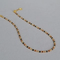 Detailansicht der facettierten schwarzen und bernsteinfarbenen Perlenkette mit Goldperlen - Halskette