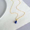 Gros plan d'un pendentif en lapis-lazuli avec fine chaîne perlée dorée sur du lin - Style pendentif en lapis-lazuli